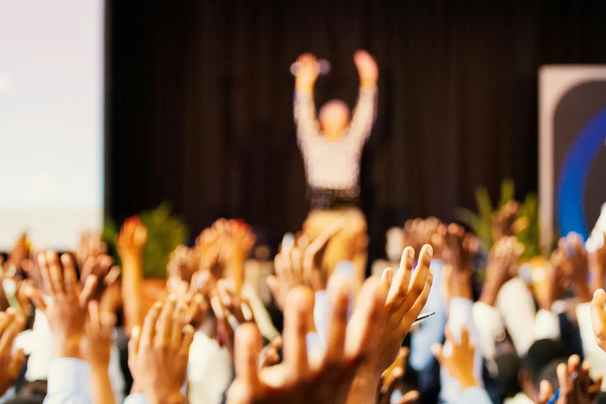 Menschen im Seminarpublikum strecken die Hände nach oben