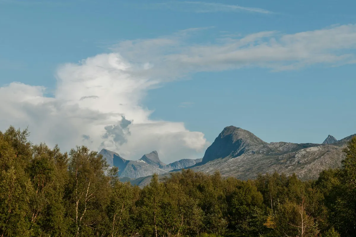 Ein stiller See spiegelt Berge und Wolken an einem klaren Tag
